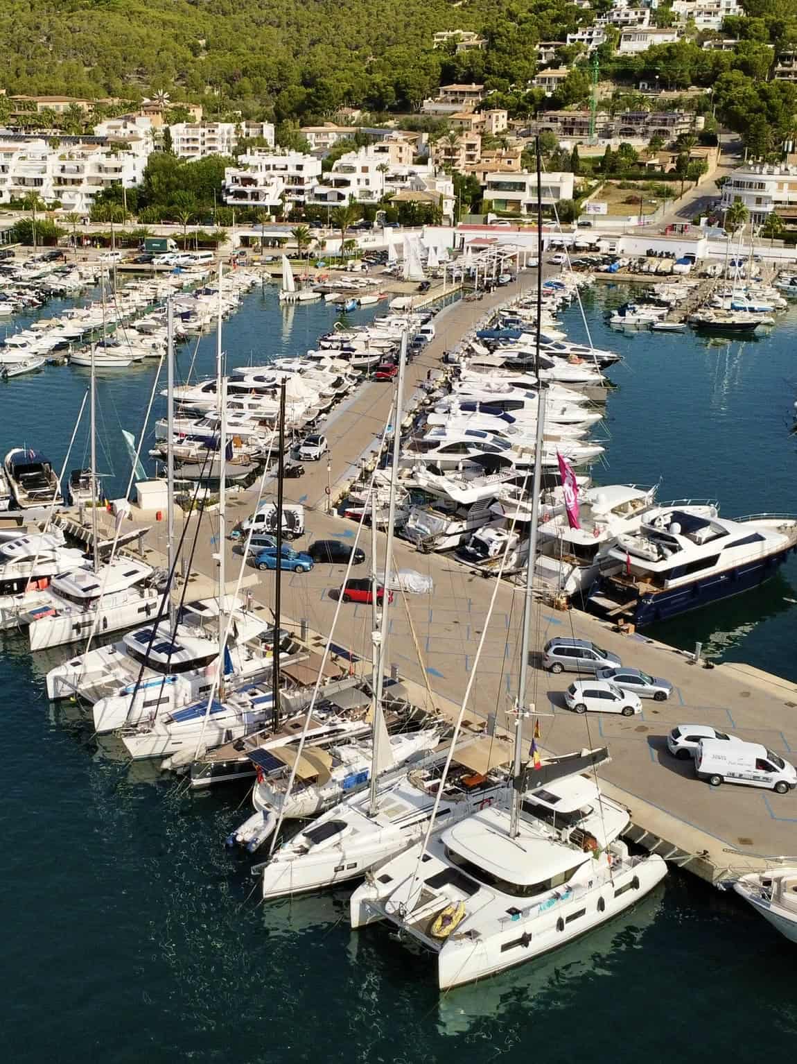 Luxurious marina filled with white yachts and sailing boats, surrounded by modern residential buildings and lush green hills, showcasing premium boat storage and scenic coastal views – Pikasea.
