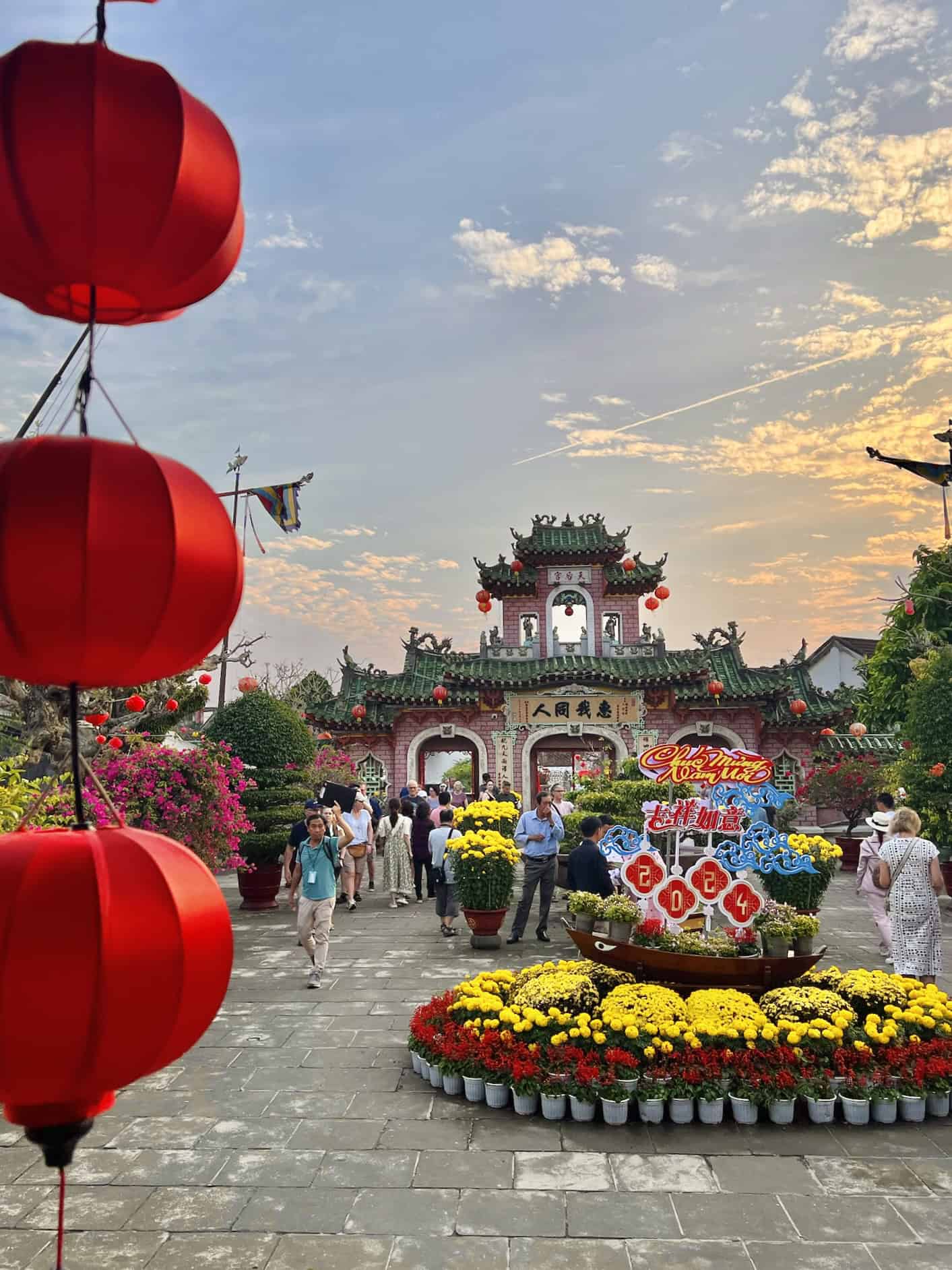 Colourful traditional Asian entrance decorated for Lunar New Year celebration with lanterns, flowers, and festive banners in a vibrant cultural setting.