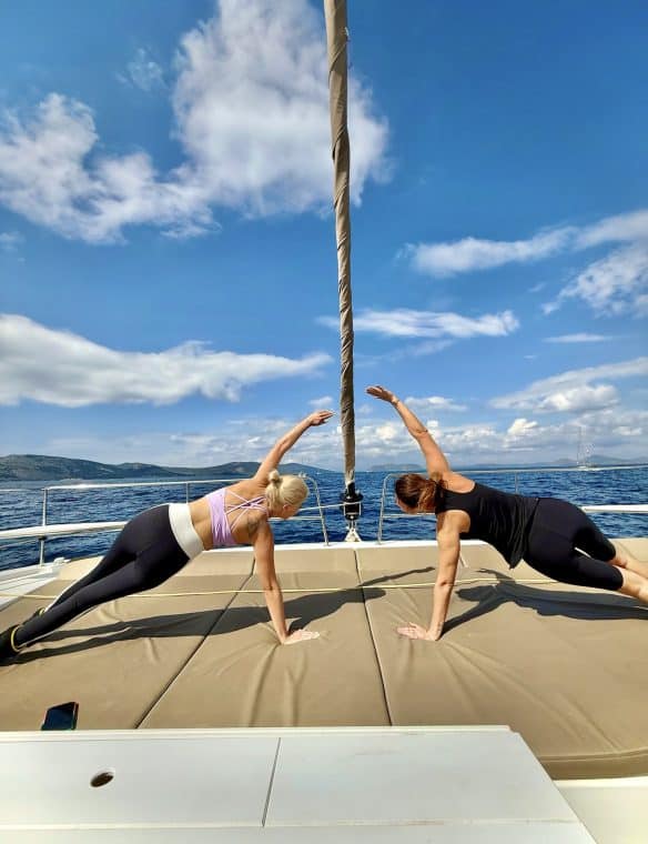 Sunset yoga on a yacht, women doing side plank pose with ocean view, relaxation, fitness, wellness, summer activity, sailing lifestyle, seascape, healthy lifestyle, outdoor exercise, sea breeze, leisure, luxury travel, boat adventure, sea scenery, yoga class, ocean horizon, wellness retreat, vacation activity, water sports, wellness yoga.