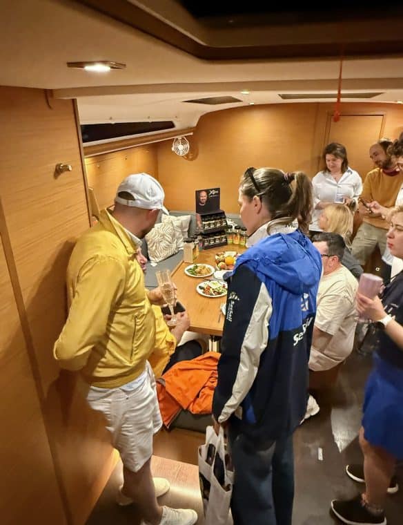 Chessboard gourmet food tasting event during exclusive gathering in cozy indoor setting with wooden decor and group of people enjoying culinary experience in a yacht cabin setting.