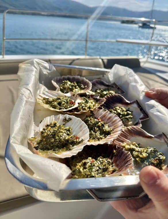 Freshly prepared stuffed scallops on a boat deck with a scenic ocean view in the background, highlighting seafood delicacies and luxury yachting experiences.