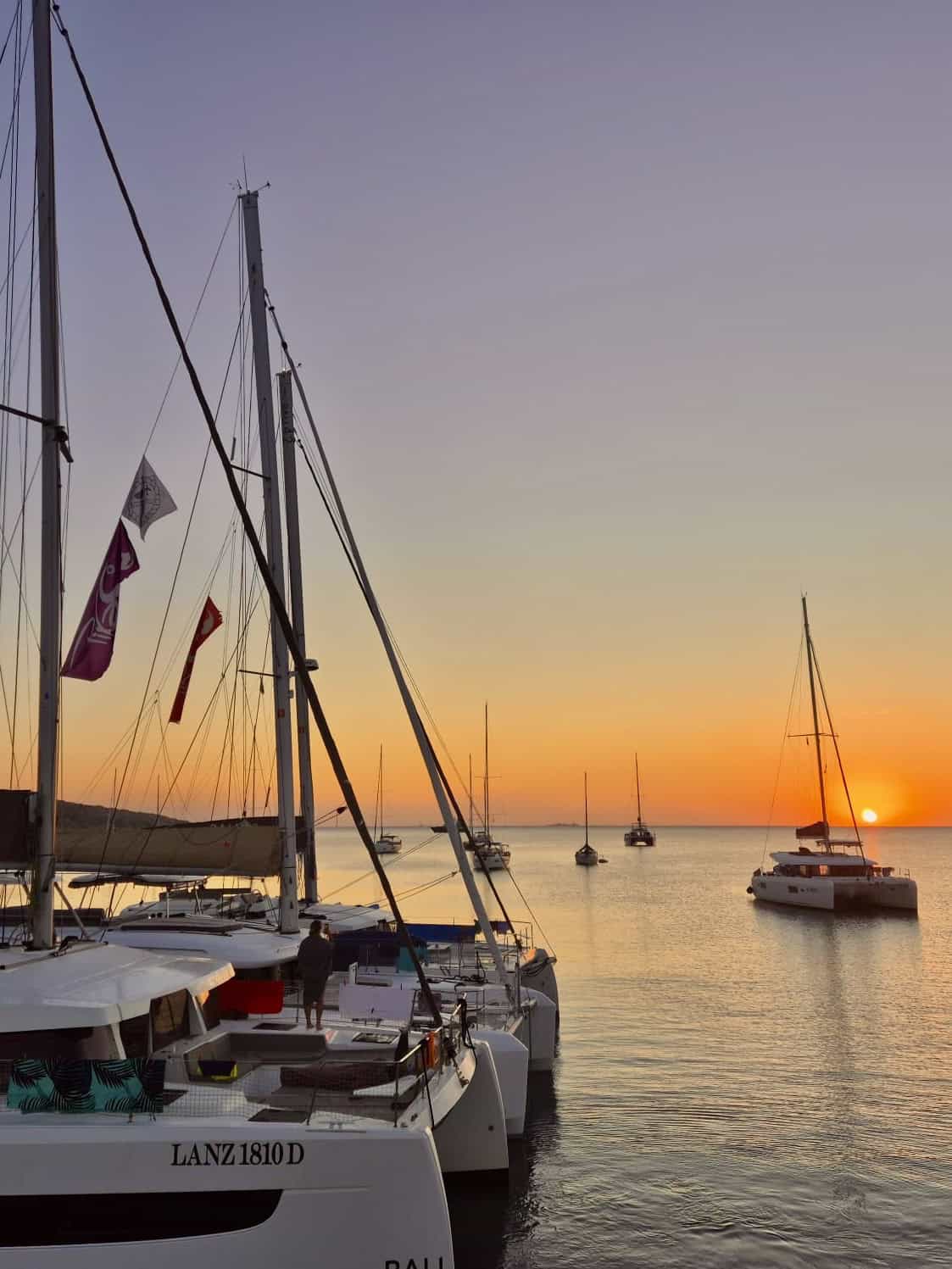 Sailboats docked at sunset port, tranquil sea scene with colourful sky and sailing yachts, perfect for yachting, marine adventures, and nautical travel imagery.