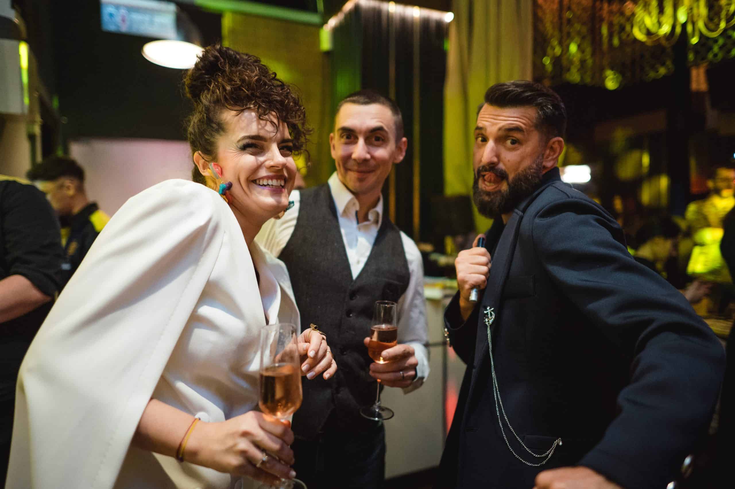 Celebrating at a lively party with friends, holding glasses of rosé wine, dressed stylishly for the event, vibrant atmosphere with colourful lighting, capturing joyful moments and companionship.