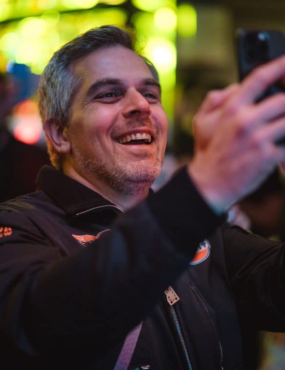 Joyful man taking a selfie at Pikasea event, vibrant background, enjoying the moment.