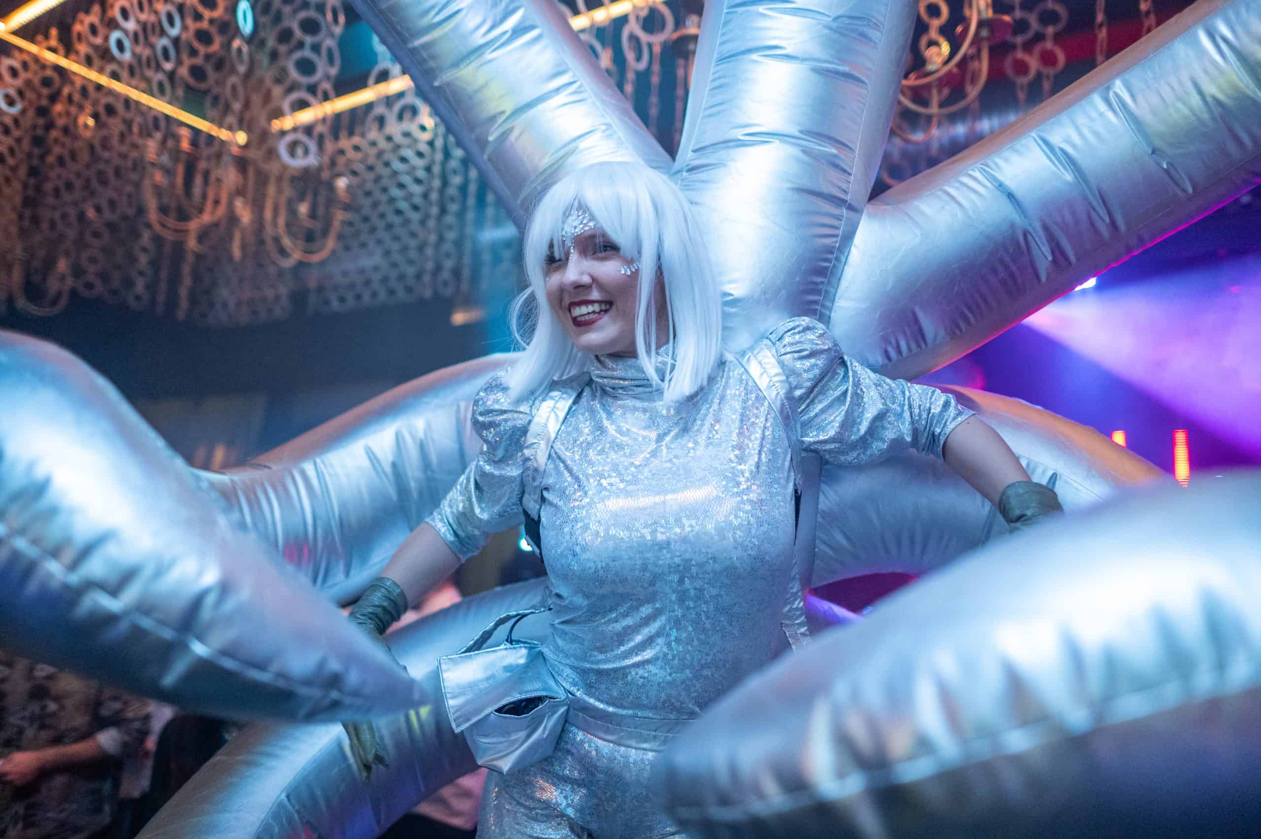 Futuristic performer in a silver costume with an elaborate star-shaped prop at a vibrant event, showcasing innovative entertainment, immersive atmosphere, and creative show elements.